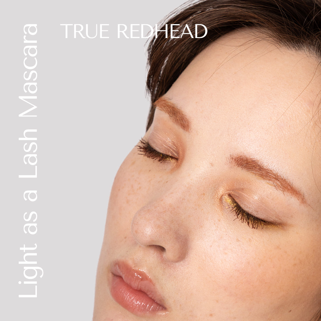 Close-up of a person's face with 'True Redhead' mascara product name on a light gray background