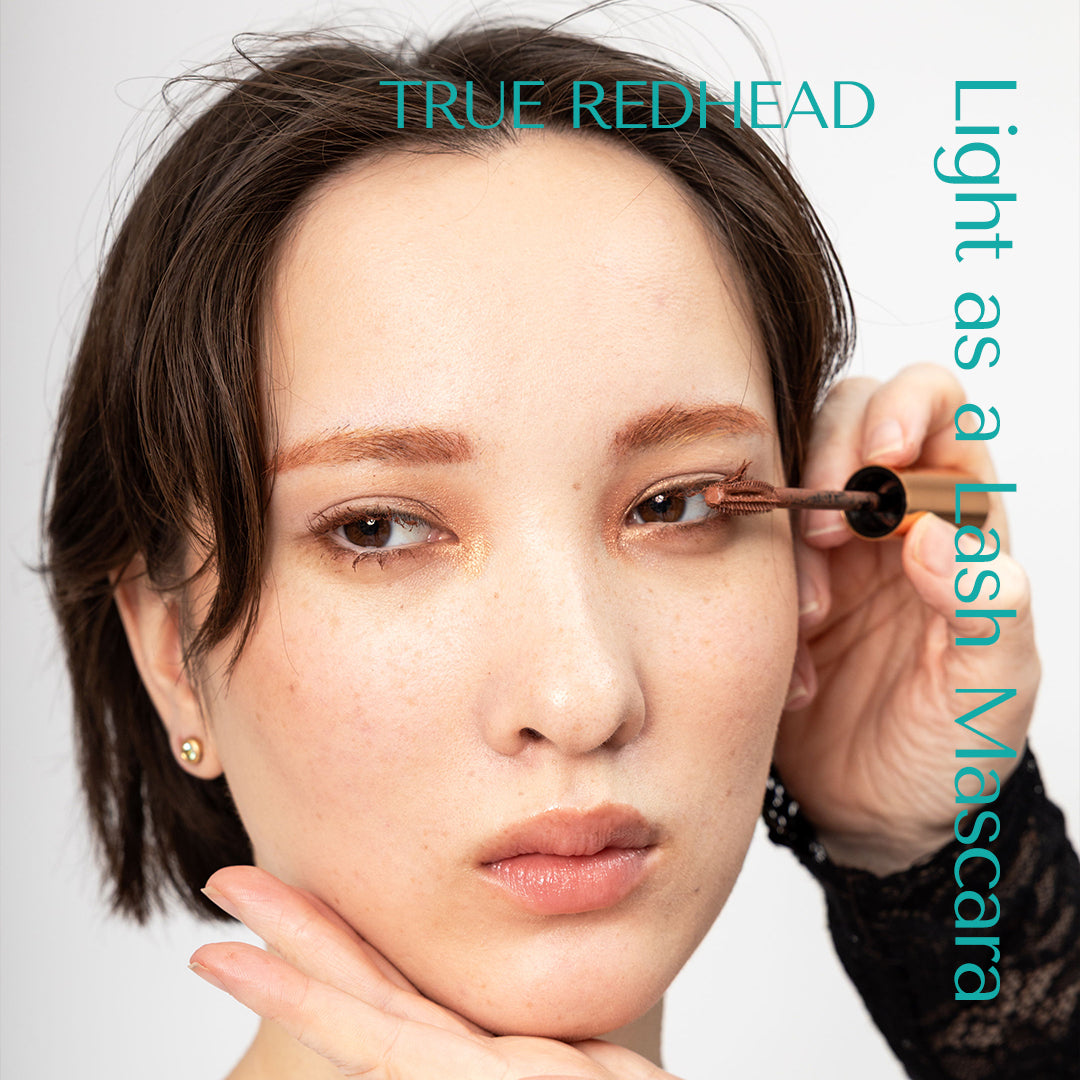 Make up artist applies mascara from light as a lash mascara on warm brown eyes. vietnamese model with creative brows wearing true redhead mascara. 