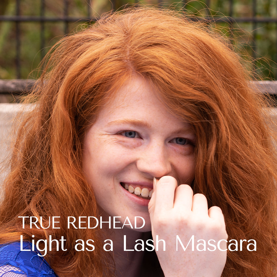 Woman with red hair smiling outdoors, with text 'True Redhead Light as a Lash Mascara'.
