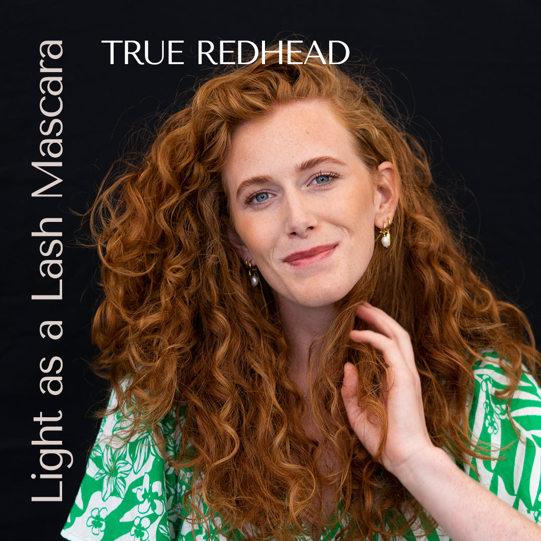 model with red curls. True redhead mascara on stunning redhead in a green dress. black backdrop. 